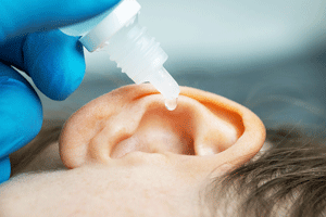 hydrogen peroxide droplets being put into a white child's ear